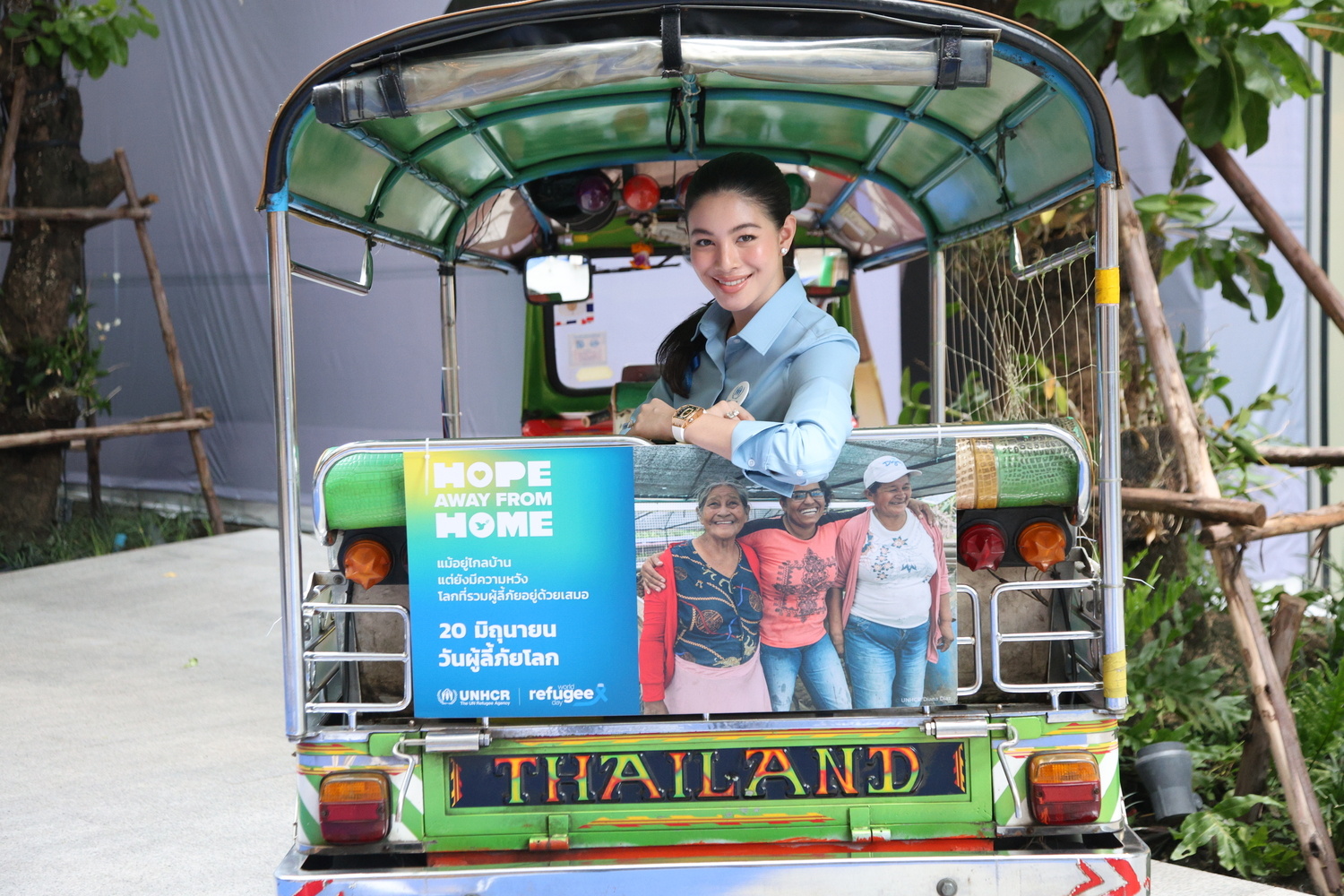 A woman looks out of the back of a stationary tuk tuk.