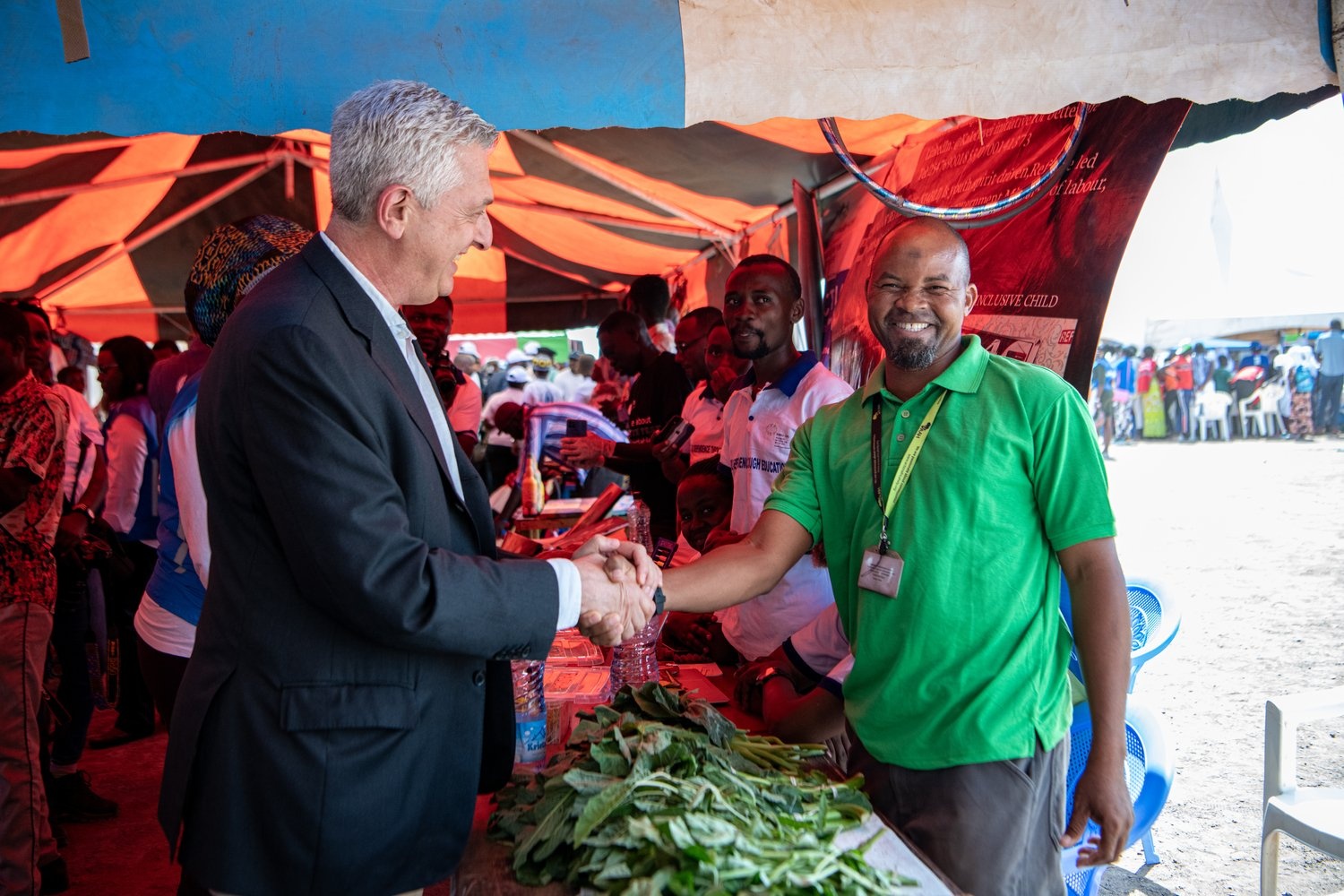 Two men shake hands at a vegetable stall.