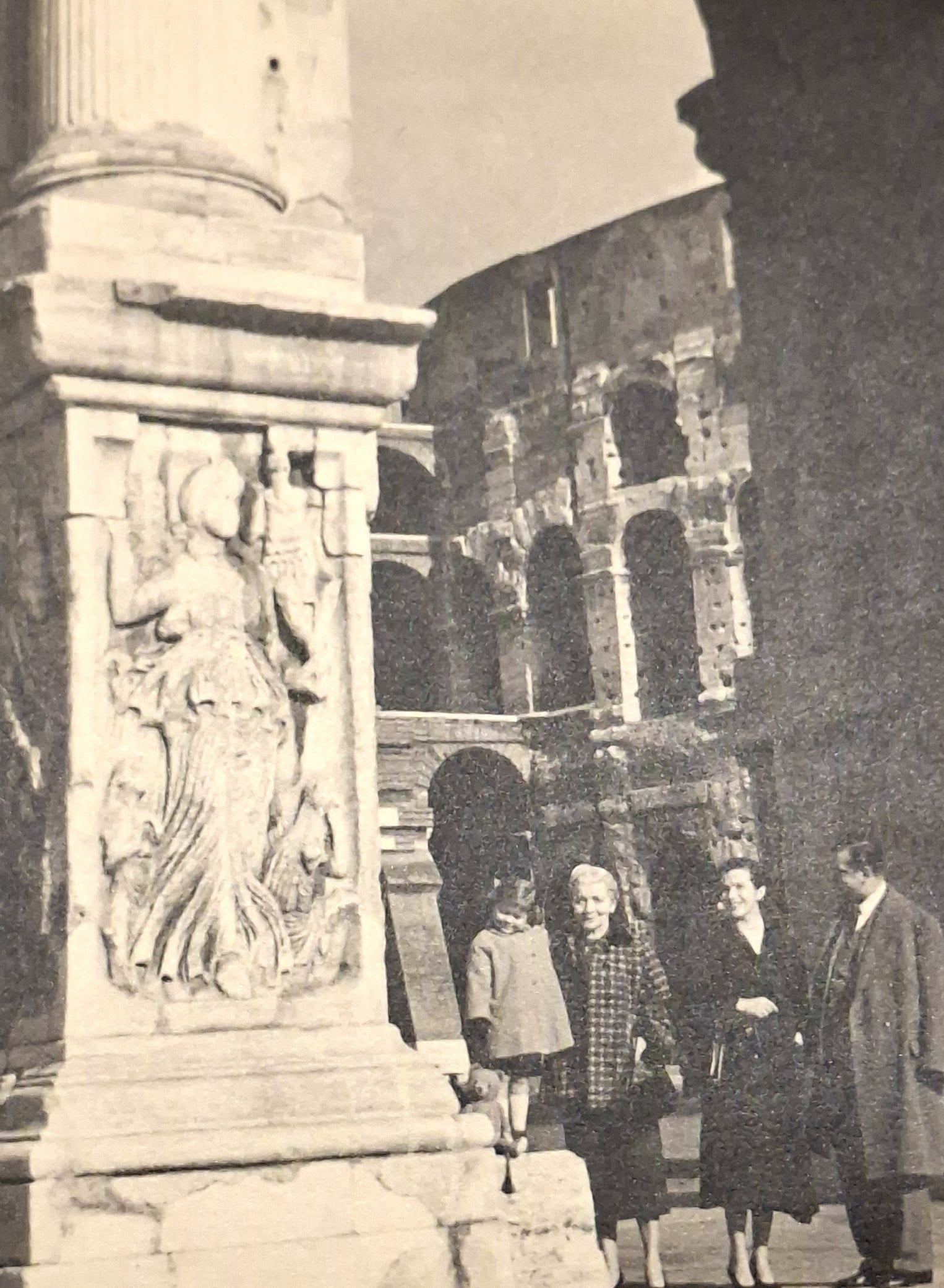 A sepia-coloured image of a family in 1950s clothing standing in a large, historical square
