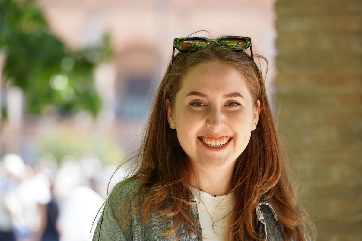 A head and shoulders portrait of a young smiling woman with sunglasses on her head.