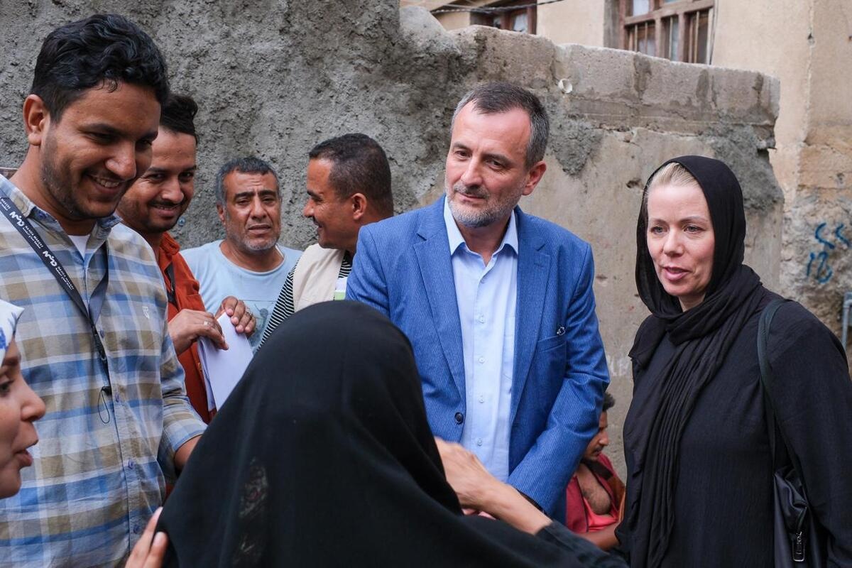 A group of people listen to a woman speaking