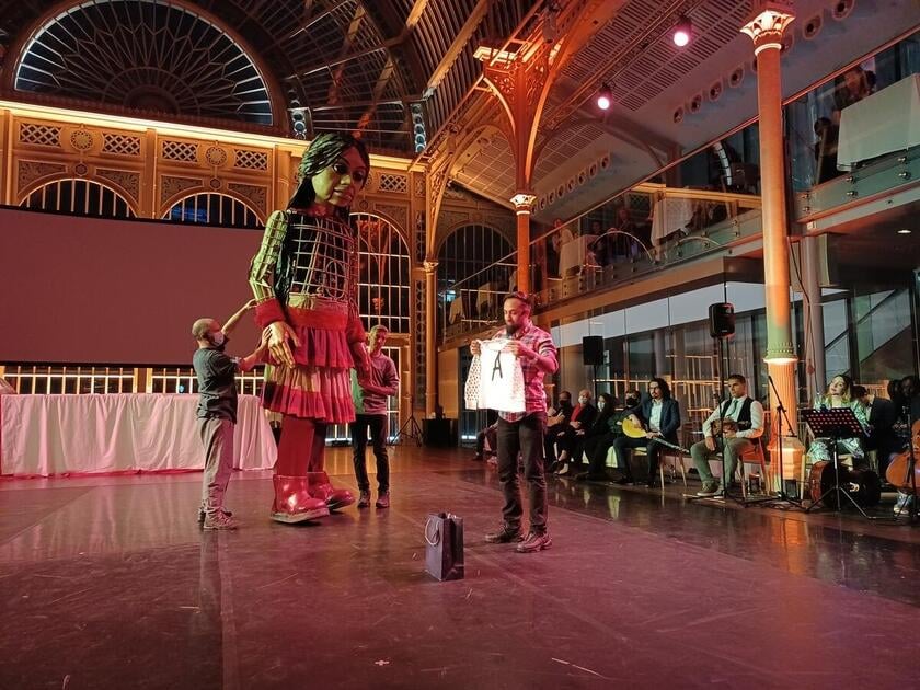 Syed Haleem from Phosphorus Theatre gives Little Amal pyjamas to help her get a good night sleep in London. 'I hope they fit you' he told her.