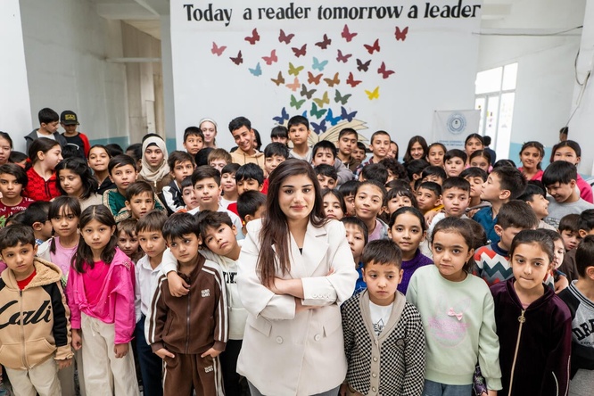 A woman stands in the middle of a classroom full of young students