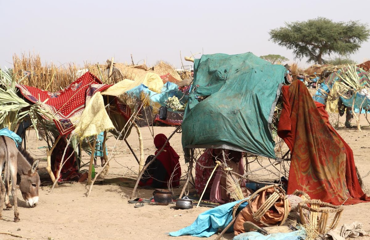 Sudanese refugees sit in the shade under makeshift shelters in the Chadian desert