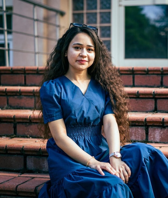 Roshin sits outside on stairs at the university campus