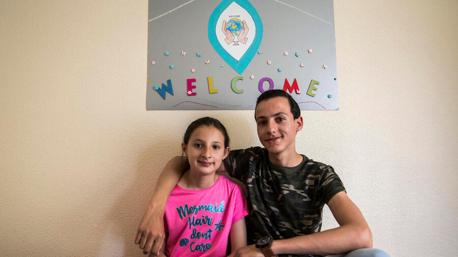 Liverpudlians welcome Syrian family to Merseyside. Two children underneath a 'Welcome' banner