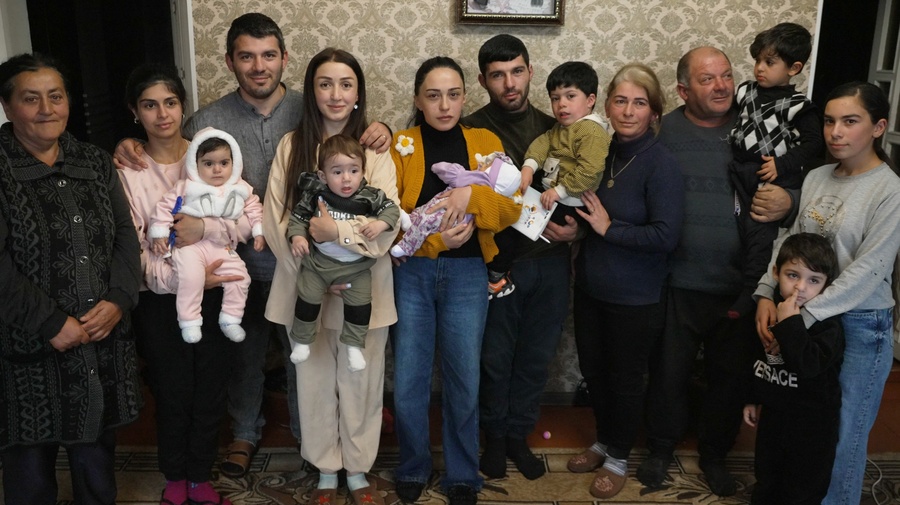 A family stand for a group photo in the living room of their home.