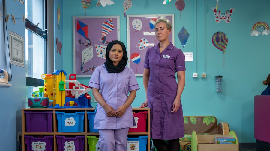 two women stand next to each other in a hospital ward
