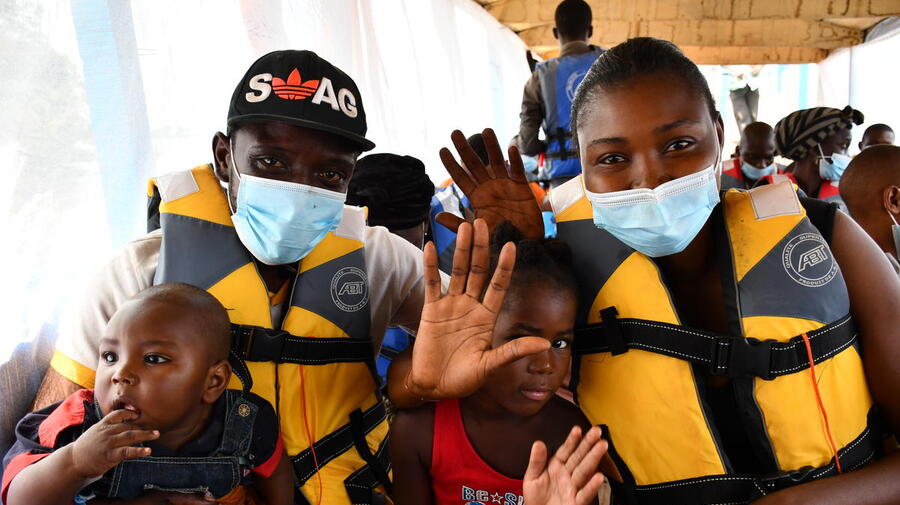 Central African returnees wave as the boat carrying them back to their homeland leaves Zongo in the Democratic Republic of the Congo, November 2020.