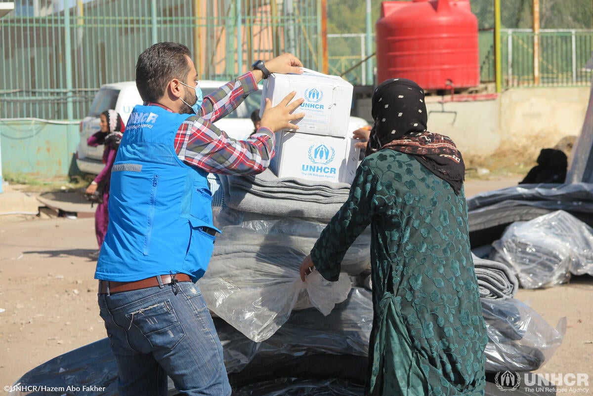 Two people unpack UNHCR boxes and blankets in Syria