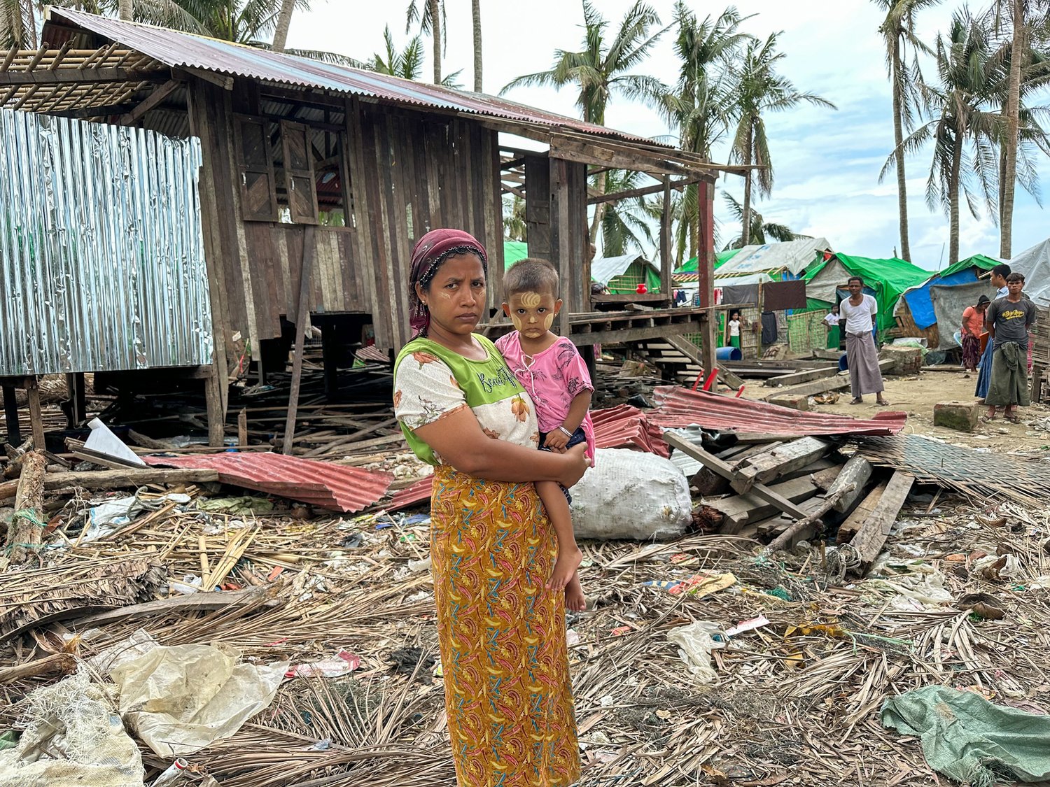 A woman holds her small child surrounded by the debris leftover from a severe storm.