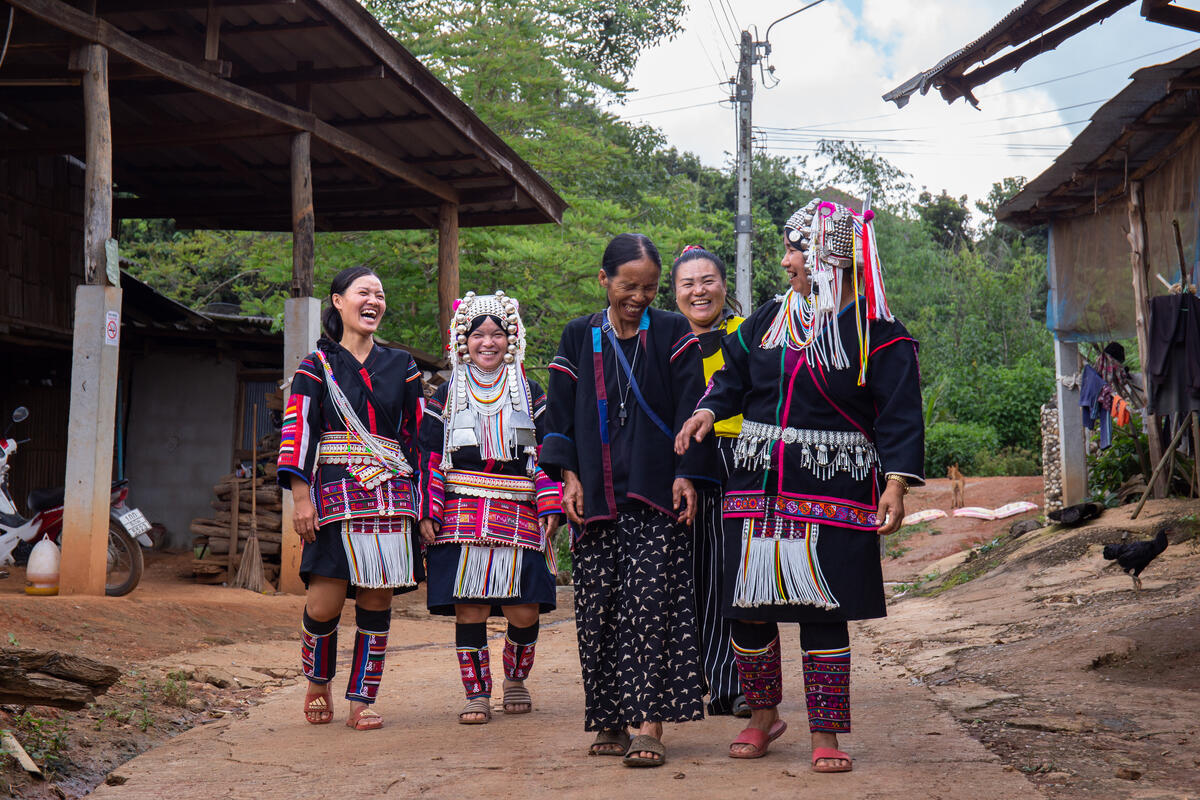 A group of women walk, laughing, through a village in Chiang Mai, Thailand.
