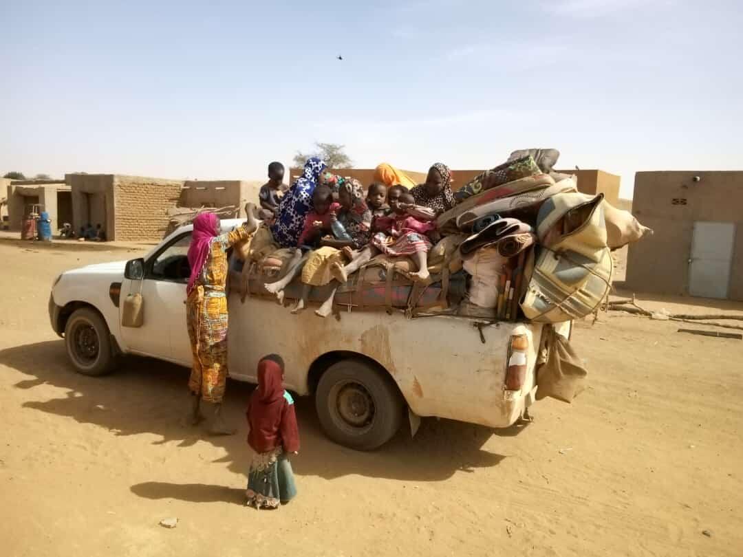 A displaced family with several young children and their belongings in a small truck, arrives in Gao, Mali, seeking refuge.
