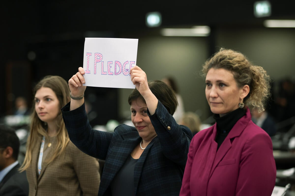 Three people holding up a sign saying 'I pledge'
