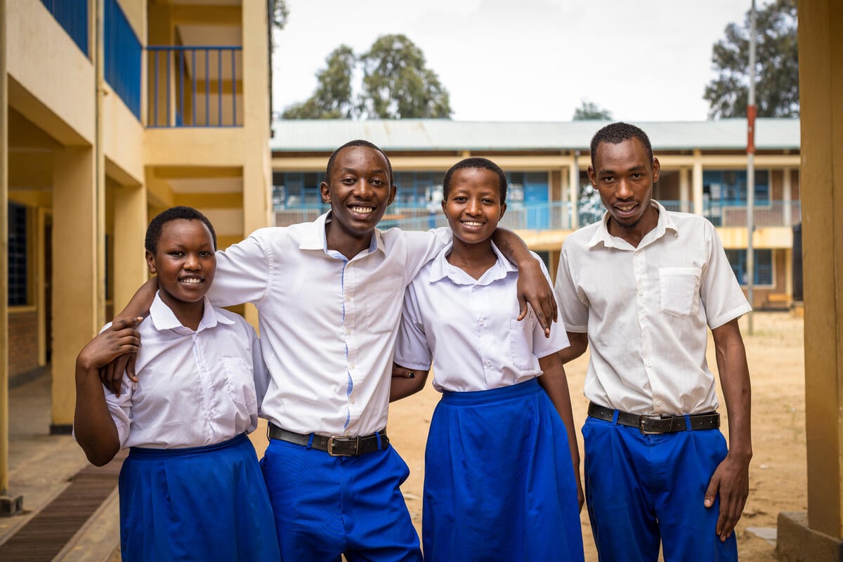 Four smiling students from the Democratic Republic of the Congo stand outside with their arms around each other