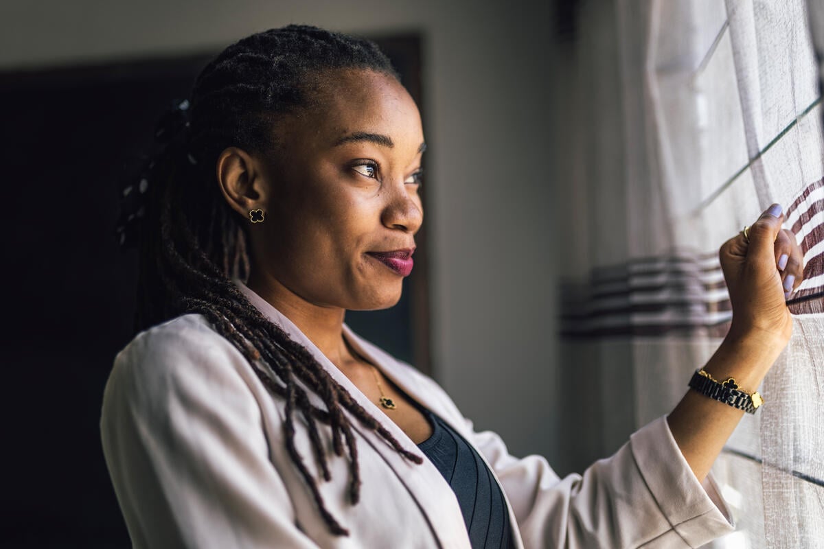 Joséphine poses next to a curtain across a window, with the light on her face