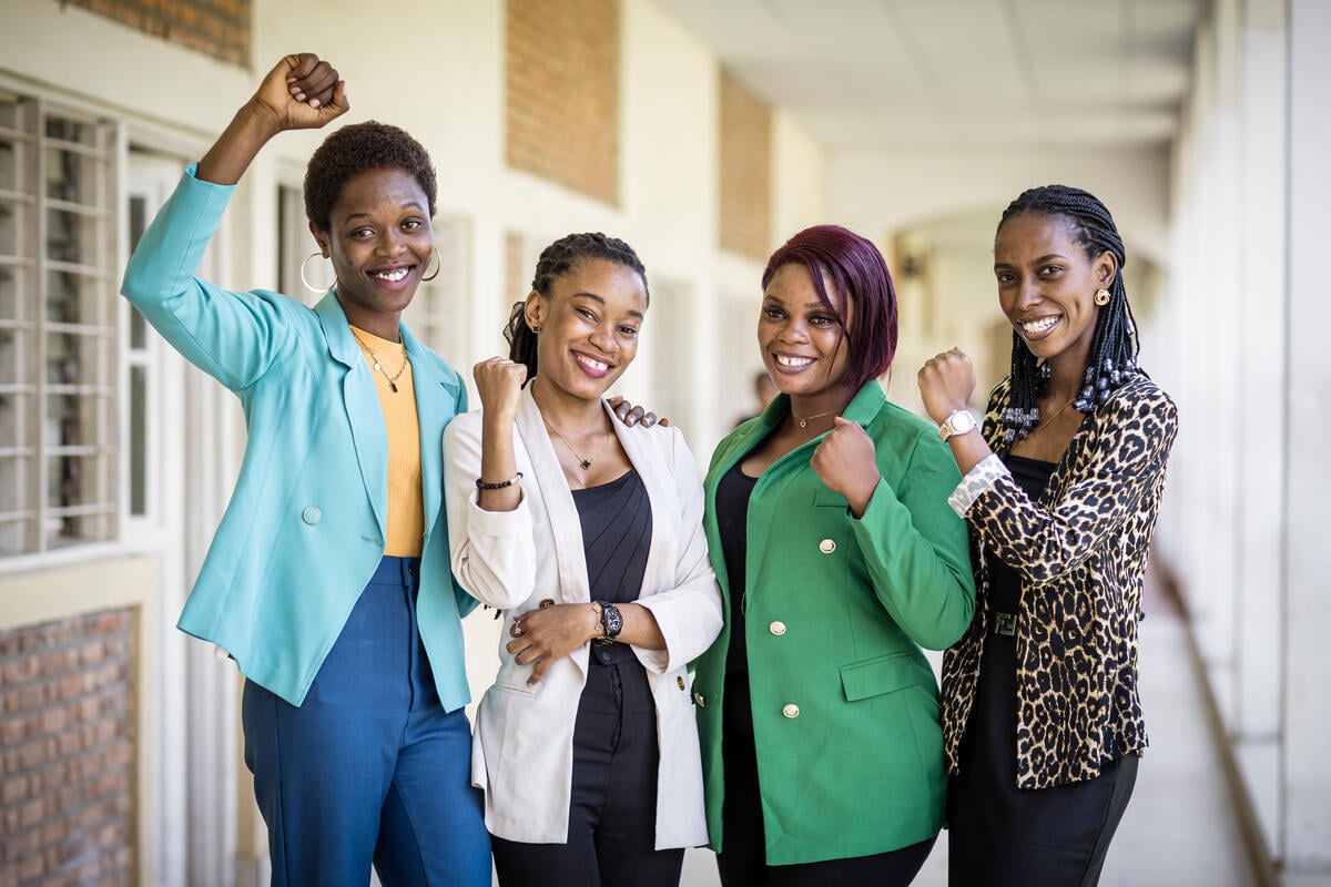 Four women pose with their fists in the air, smiling.