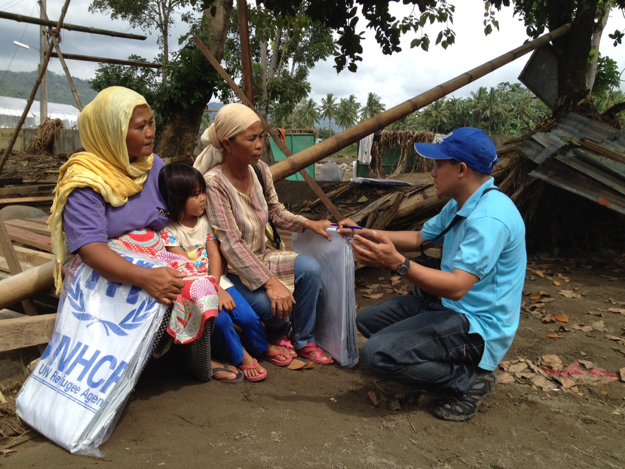 UNHCR's Rasul Kulat with beneficiaries Imelda Angud and Dairi Bansil in the ruins of Bansil's house in Mandulog village, northern Mindanao island.