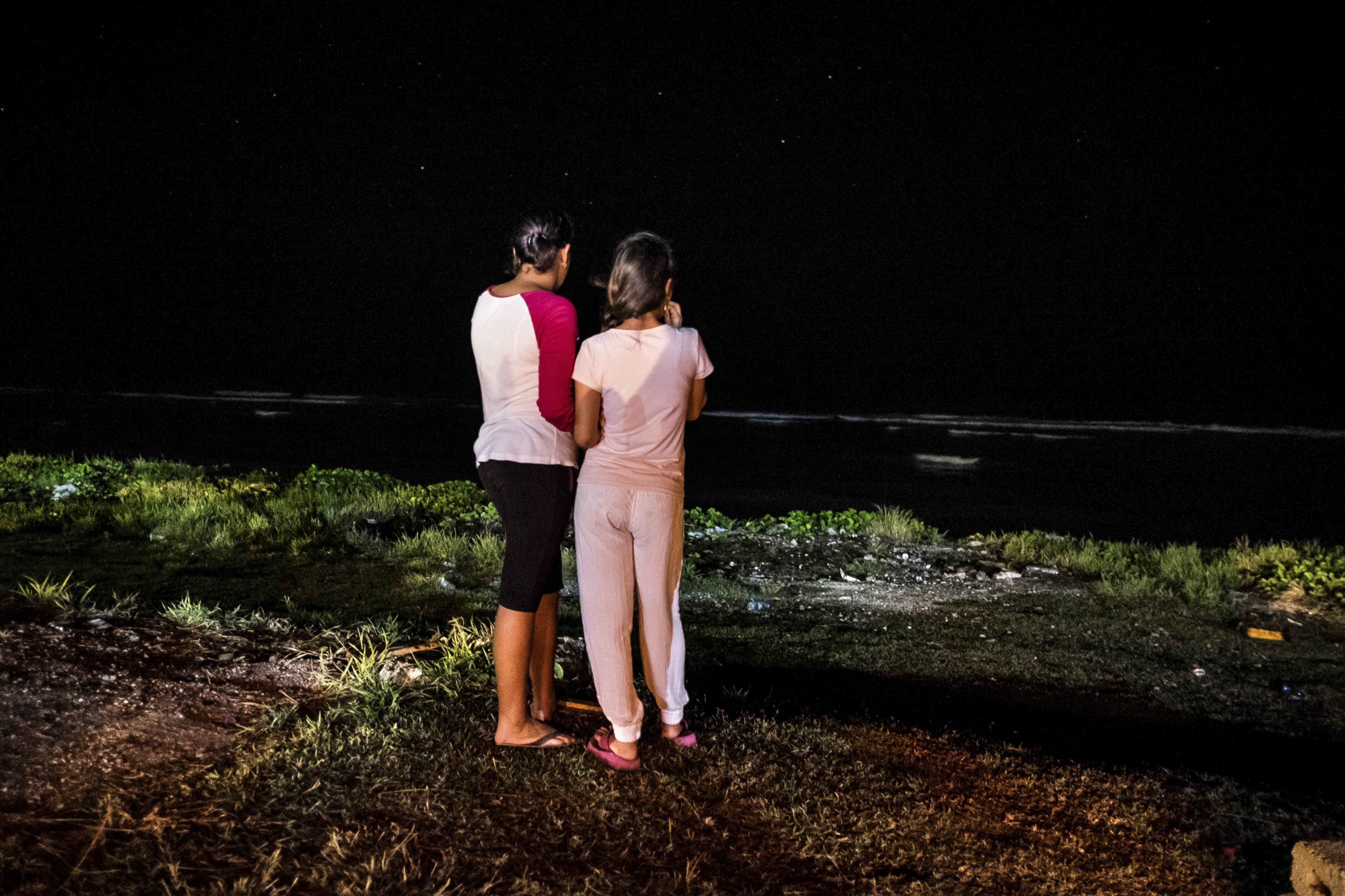 Night time. Two young women look out to sea.