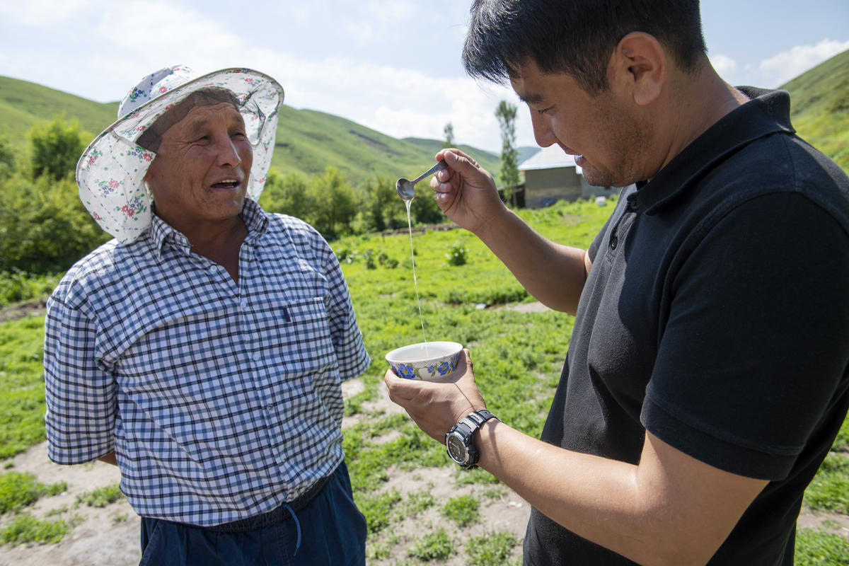 Kyrgyzstan. Nansen Refugee Award 2019 laureate Azizbek Ashurov tasting the honey of Abdusamat Saparov