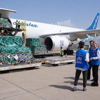 UNHCR staff stand beside a plane delivering supplies.