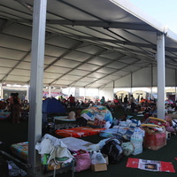 A temporary shelter filled with supplies and people in the background