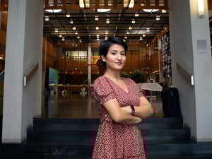 A woman with folded arms stands in front of a conference venue in Geneva.