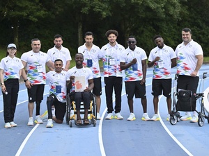 Athletes in matching uniforms pose for a group photo on a running track