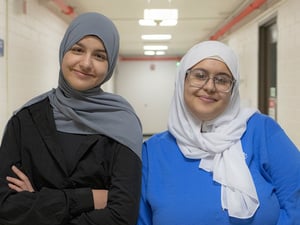 Sisters Linda and Neriman standing together in a hallway. 