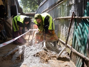 Rohingya refugee women in Cox's Bazar refugee camp working together to pave alleyways.