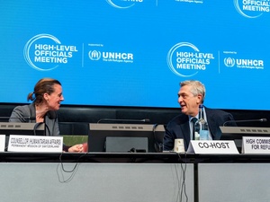 A woman and a man face each other at the podium.