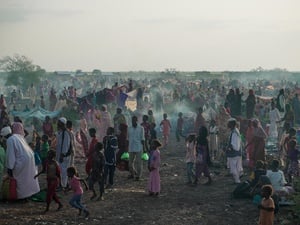 A large number of new arrivals from Sudan wait in a field in South Sudan