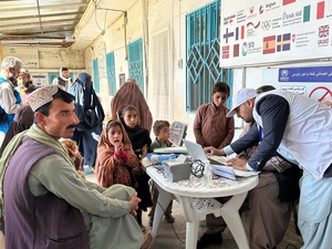 An Afghan refugee man and his young family have their details registered on a computer. 