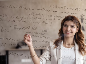 A young woman seen through transparent glass which is writing code on.