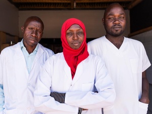 Three medical staff look at the camera, looking serious. 