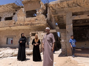 A family of four refugee returnees stand in front of a partially-collapsed building – their home in Daraa, southern Syria