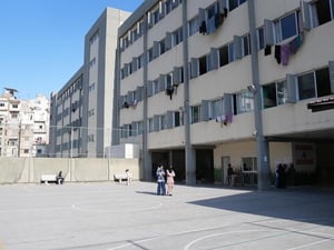 A view of a playground and school building with laundry hanging on lines out of the windows