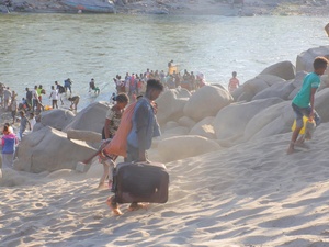 Ethiopian refugees flee across a river with their belongings.