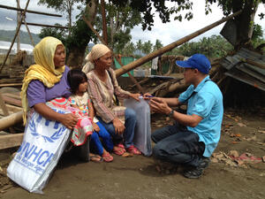 UNHCR's Rasul Kulat with beneficiaries Imelda Angud and Dairi Bansil in the ruins of Bansil's house in Mandulog village, northern Mindanao island.