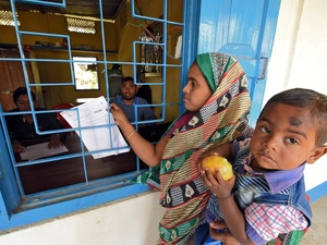 A mother carrying her son arrives to check her name on the draft list of the National Register of Citizens at an NRC centre in Chandamari village, India, 