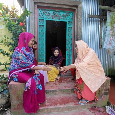 A group of women sit down together on stairs in front of a house.