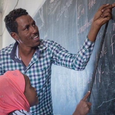A teacher and his student in front of a black board.