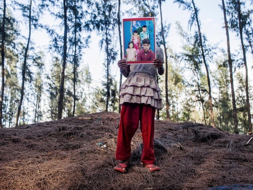 A young girl holds in front of her a photo of her lost 15-year-old brother.