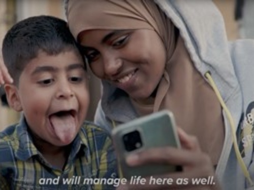 A playful mother and child look at a mobile phone