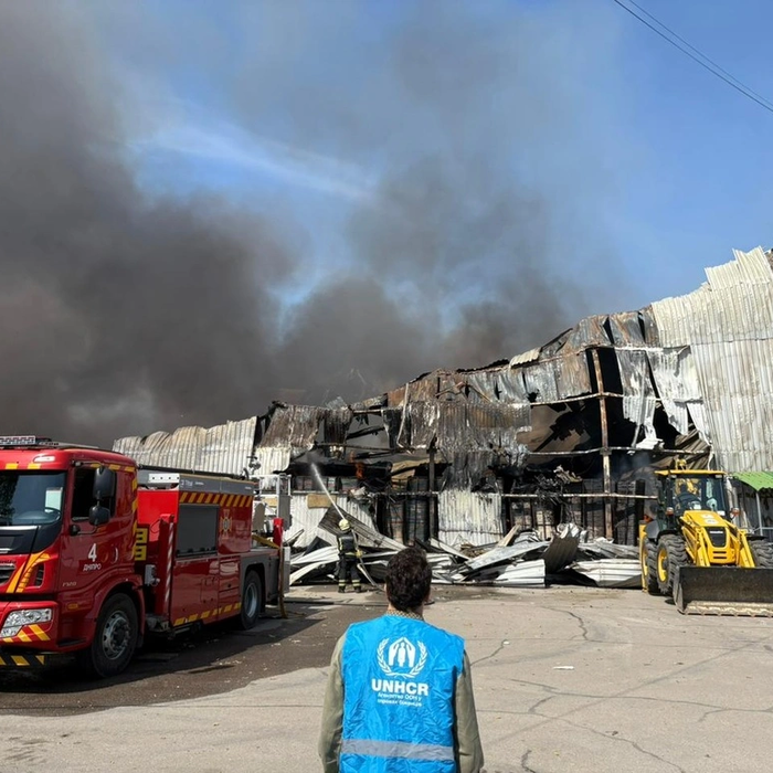 UNHCR staff member looks on as emergency workers work to put out a fire.