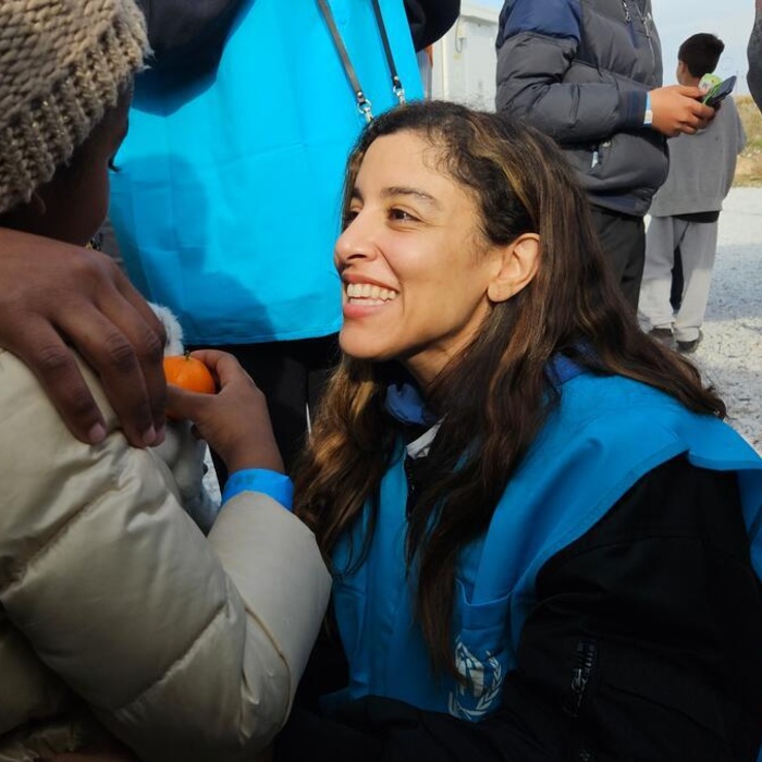 Marina Satti squats and greets a child with a huge smile.