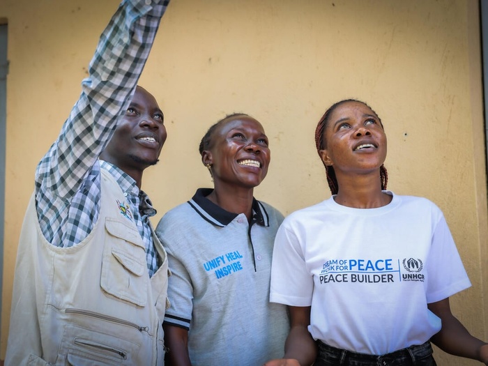 Three Youth Peace Mentors smiling at the camera in Rhino Settlement, West Nile, Uganda.