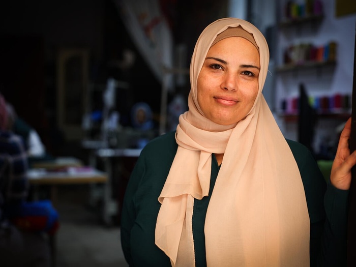 Marwa, a Syrian refugee, stands in a doorframe, looking confidently at the camera.