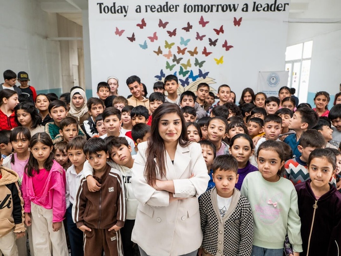 A woman stands in the middle of a classroom full of young students
