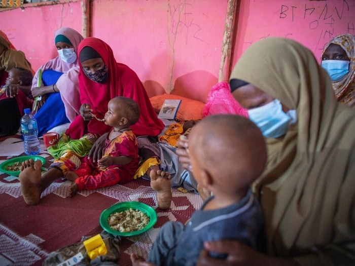 Mothers and children sit in a circle and share a meal during an Infant and Young Child Feeding counselling session.